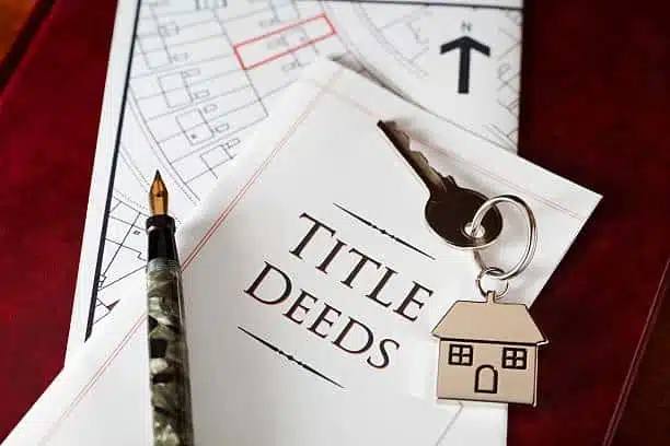 Hands transferring a Nevada property title document across a desk during a deed signing